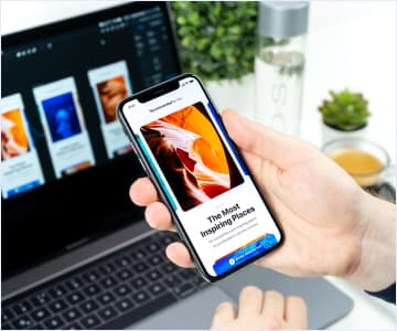 The computer is on the teble and the phone is in hand
